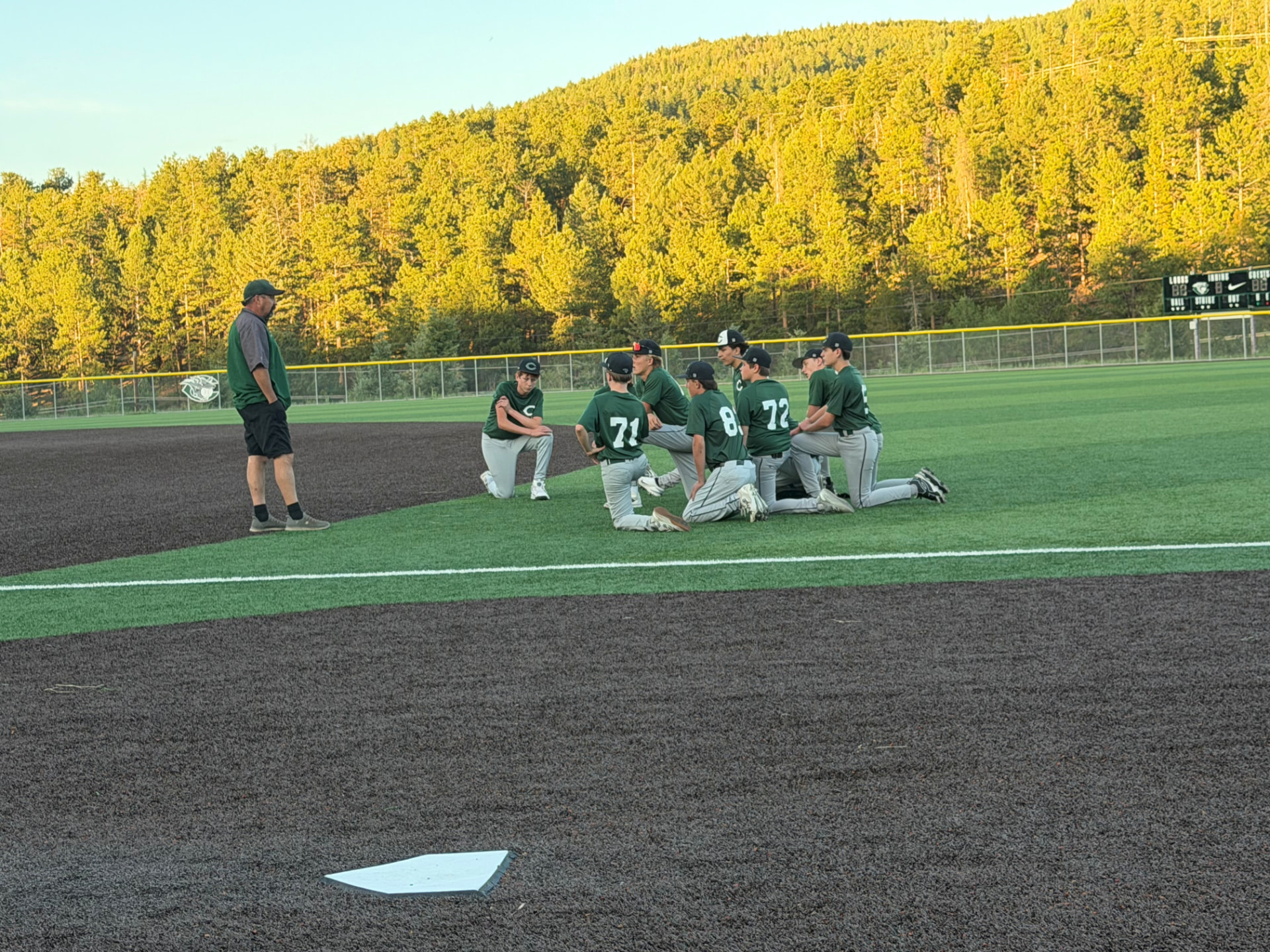 Conifer Lobos baseball team huddle on the field with mountain backdrop
